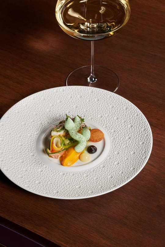 Voorgerecht met groene kruidenschuim en een glas witte wijn